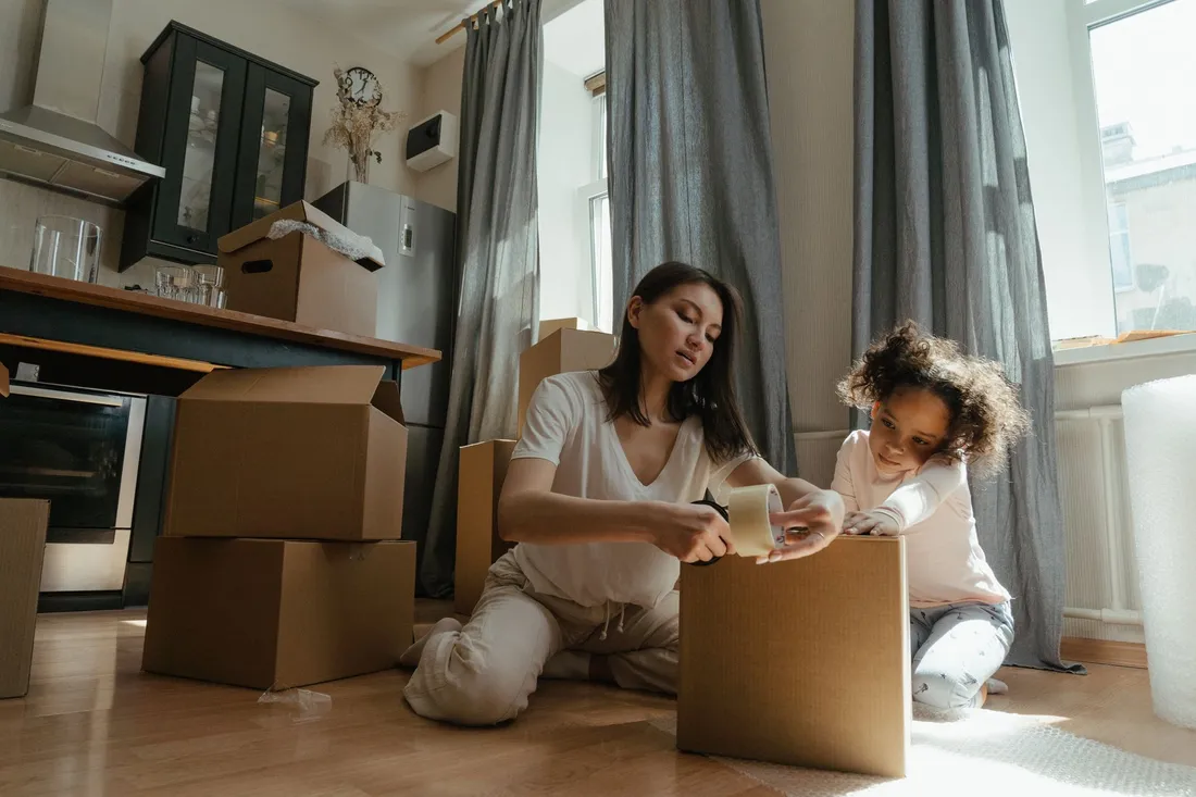 Umzugshelfer unterstützt eine ältere Dame beim Packen